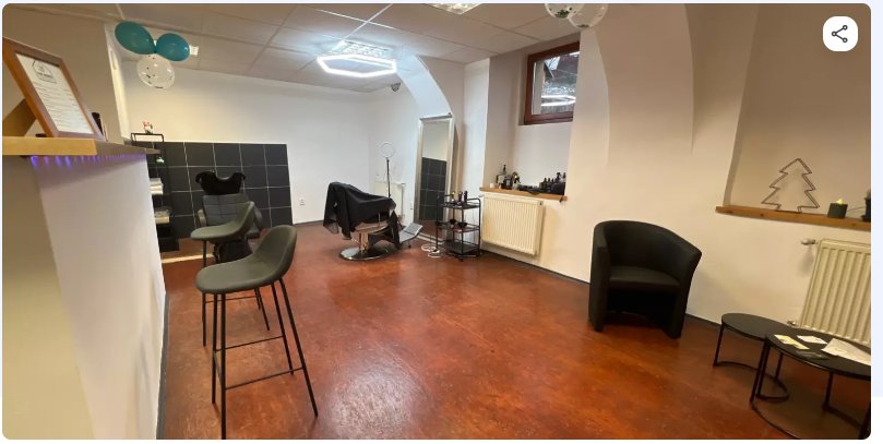 Interiér Cut House Barbershop – holičská křesla, dřevěná podlaha a tmavé obklady